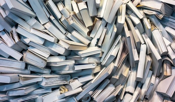 Image of many books, mostly with white covers, swirling in a vortex.
