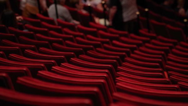 Photograph of rows of red theatre seats.