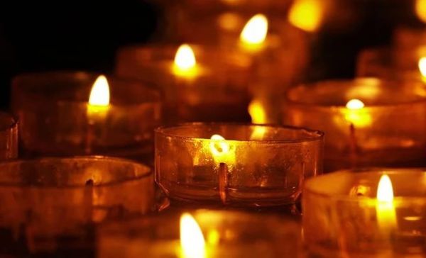 A close-up photograph of many lit votive candles.