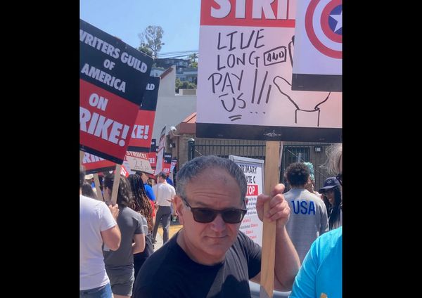 Photograph of Javi at the picket line, holding a sign that says "LIVE LONG AND PAY US" with a drawing of the Vulcan salute. Other strikers in the background holding signs.