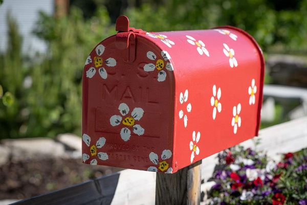 Photograph of a red mailbox with painted white and yellow flowers.