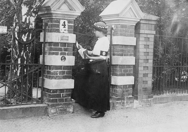 Black and white archival photo of a young woman delivering mail. 