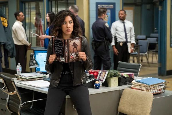 Still from B99 of Rosa reading Crimson Portal in the station