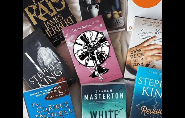 A collection of books arranged face-up, with the Fansplaining fan on one in the center.