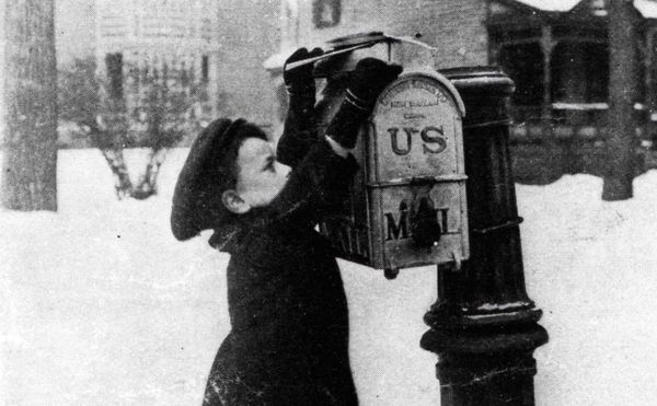 Black and white archival photo of a child mailing a letter against a snowy backdrop 