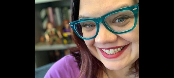 A headshot of Casey Fiesler, wearing fashionable blue glasses.