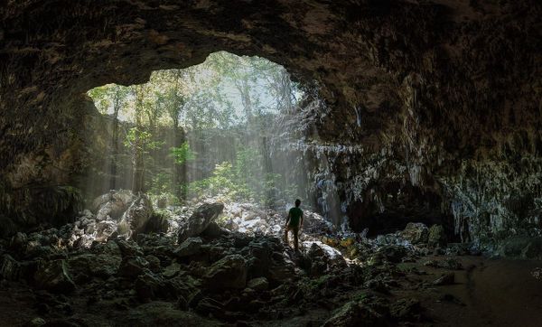 image of a figure in a cave with a large hole letting in sunlight 