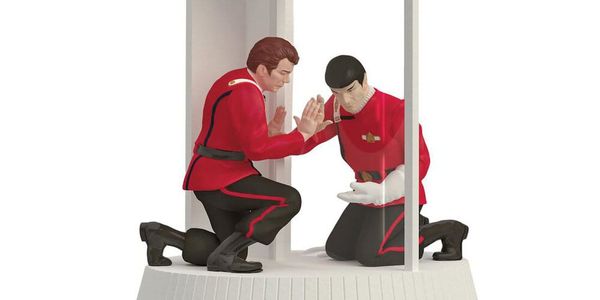  Action figure versions of Kirk and Spock touch hands but are separated by a pane of glass. 