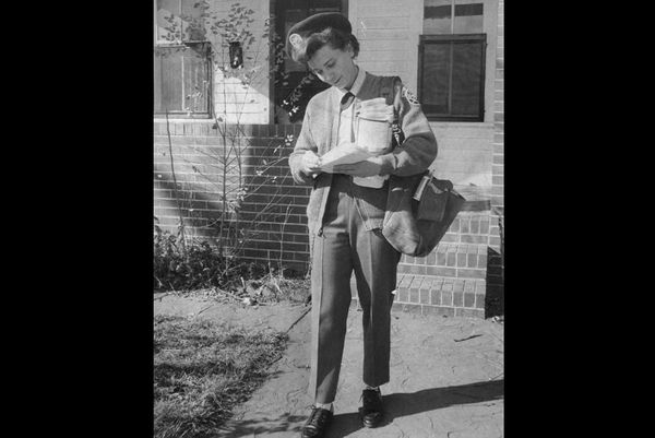 Black and white archival image of a female postal worker carrying some letters