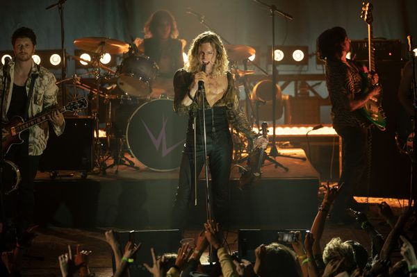 Production still from The Vampire Lestat featuring Lestat onstage with his band (Larry, TC, Salamander visible behind him), holding a violin and singing into the mic.