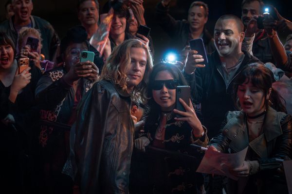 Production still featuring Lestat posing for selfies surrounded by a crowd of fans with their phones out.