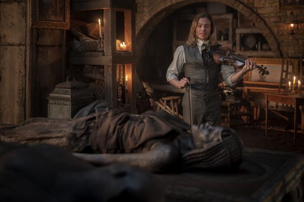 Production still of Lestat playing the violin for Akasha who is lying on her slab.