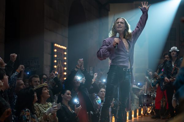 Production still featuring Lestat performing on a stage, his arm stretched upwards.