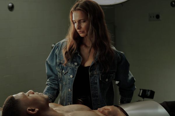Production still of Zoe healing John as he lays shirtless on a hospital bed.