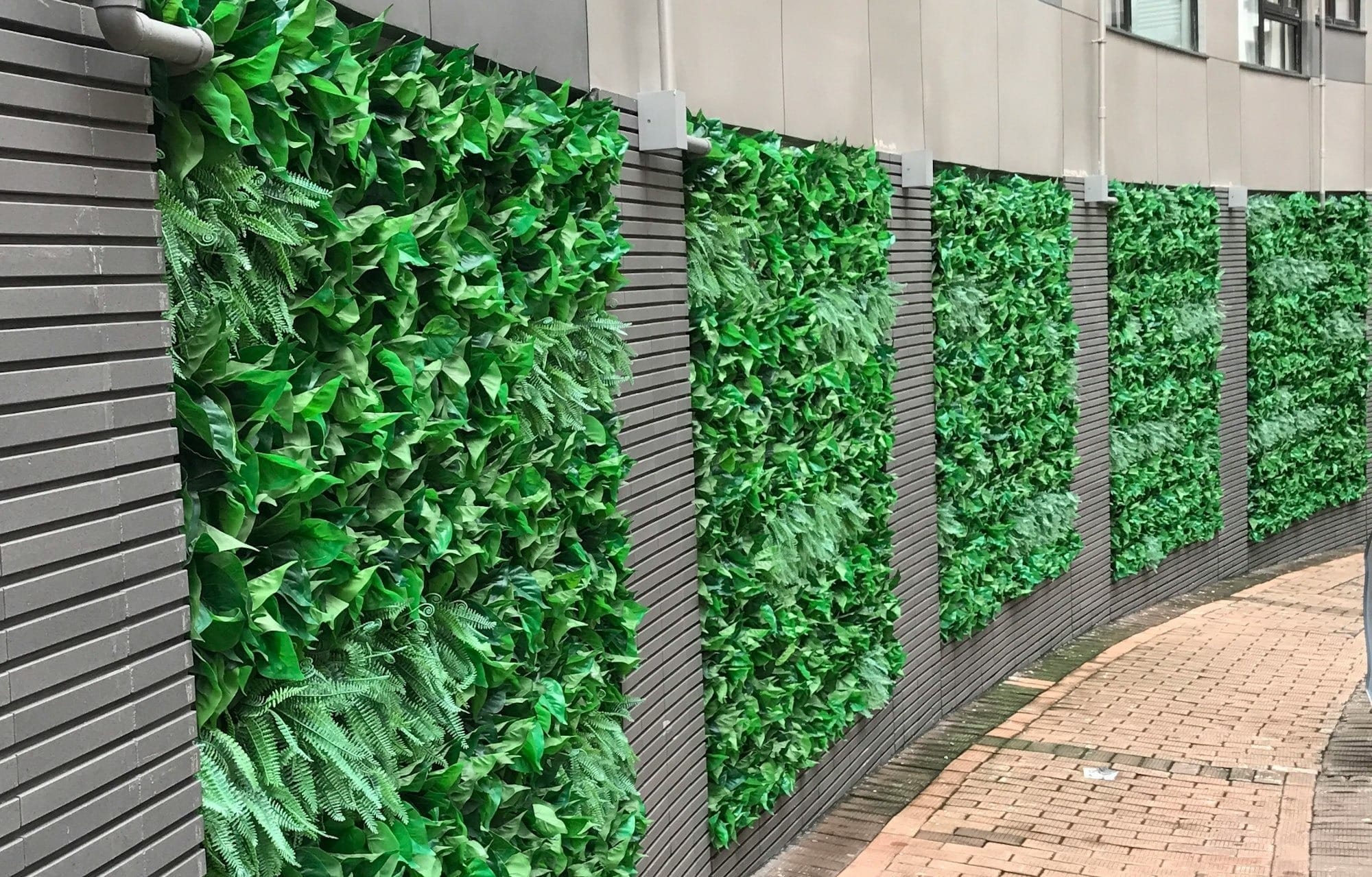 a brick sidewalk next to a green wall