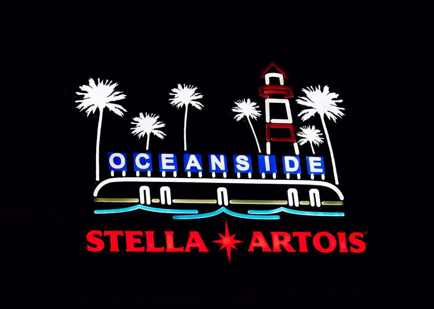 an illuminated Stella Artois bar sign that features the O C E A N S I D E bay letters