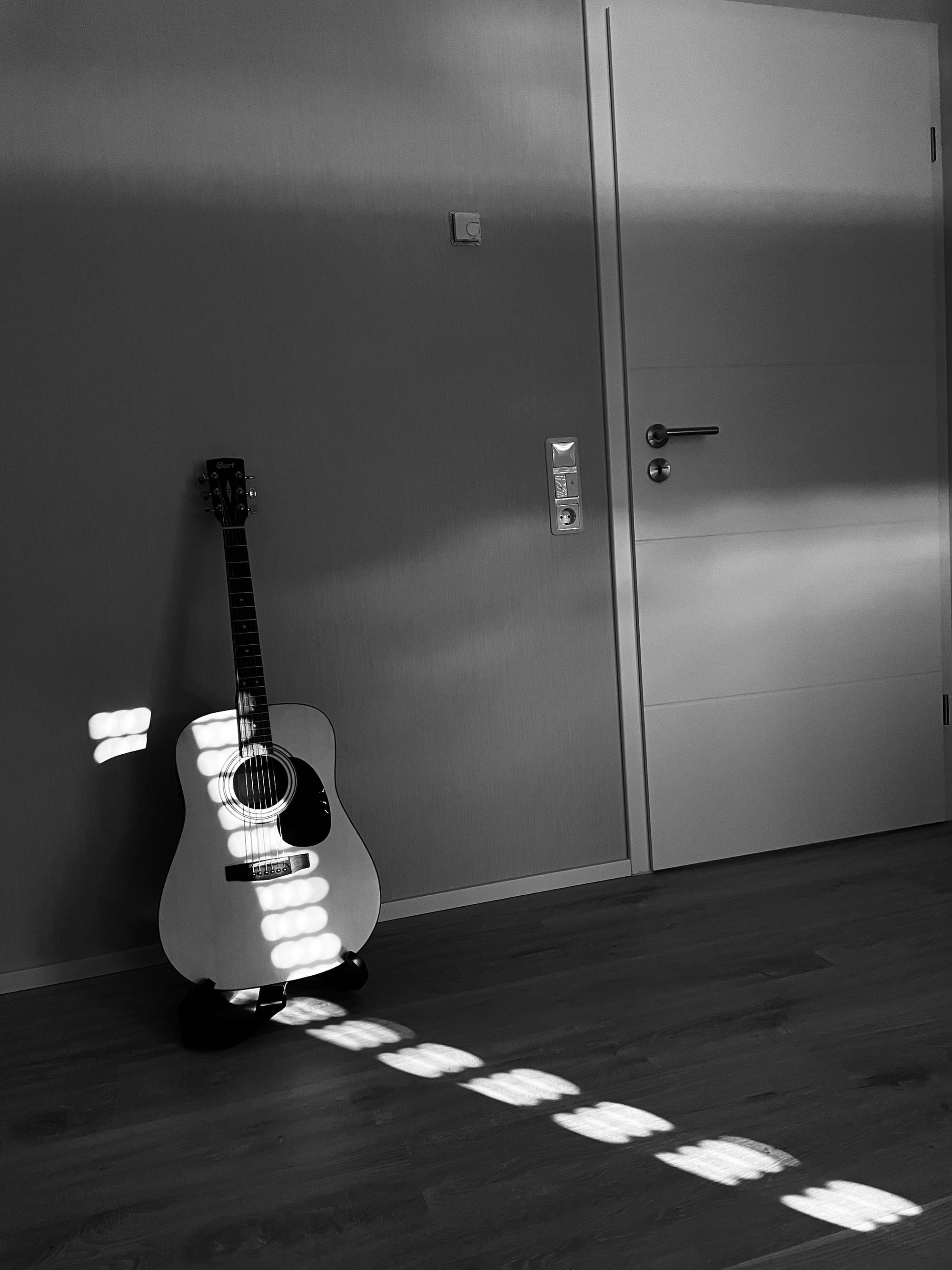 Image of a lonely guitar in a dark room waiting to be picked up 