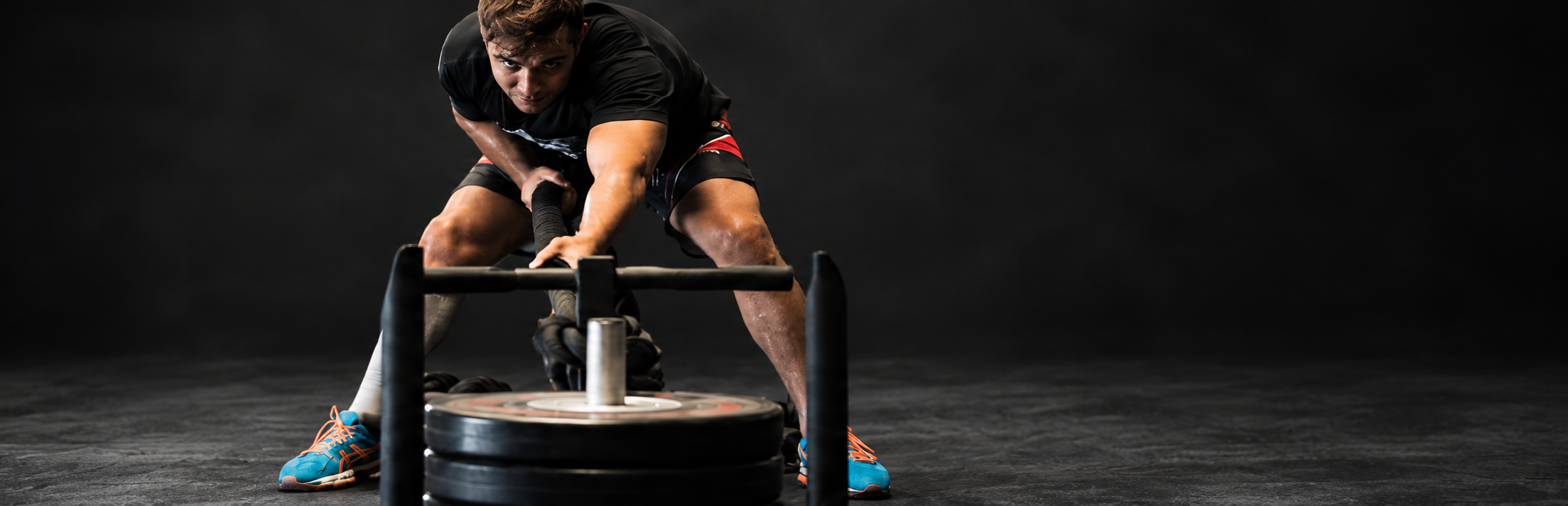 Editorial composite of a grappler training with a weighted sled.
