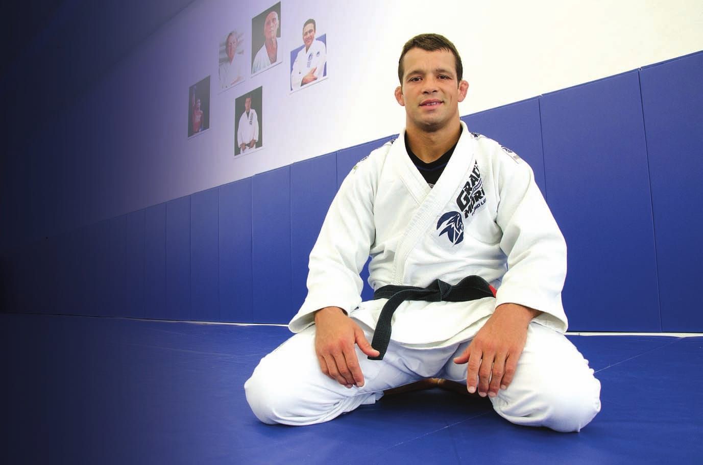 Fabio Leopoldo seated on blue academy mats, wearing a white gi and black belt.