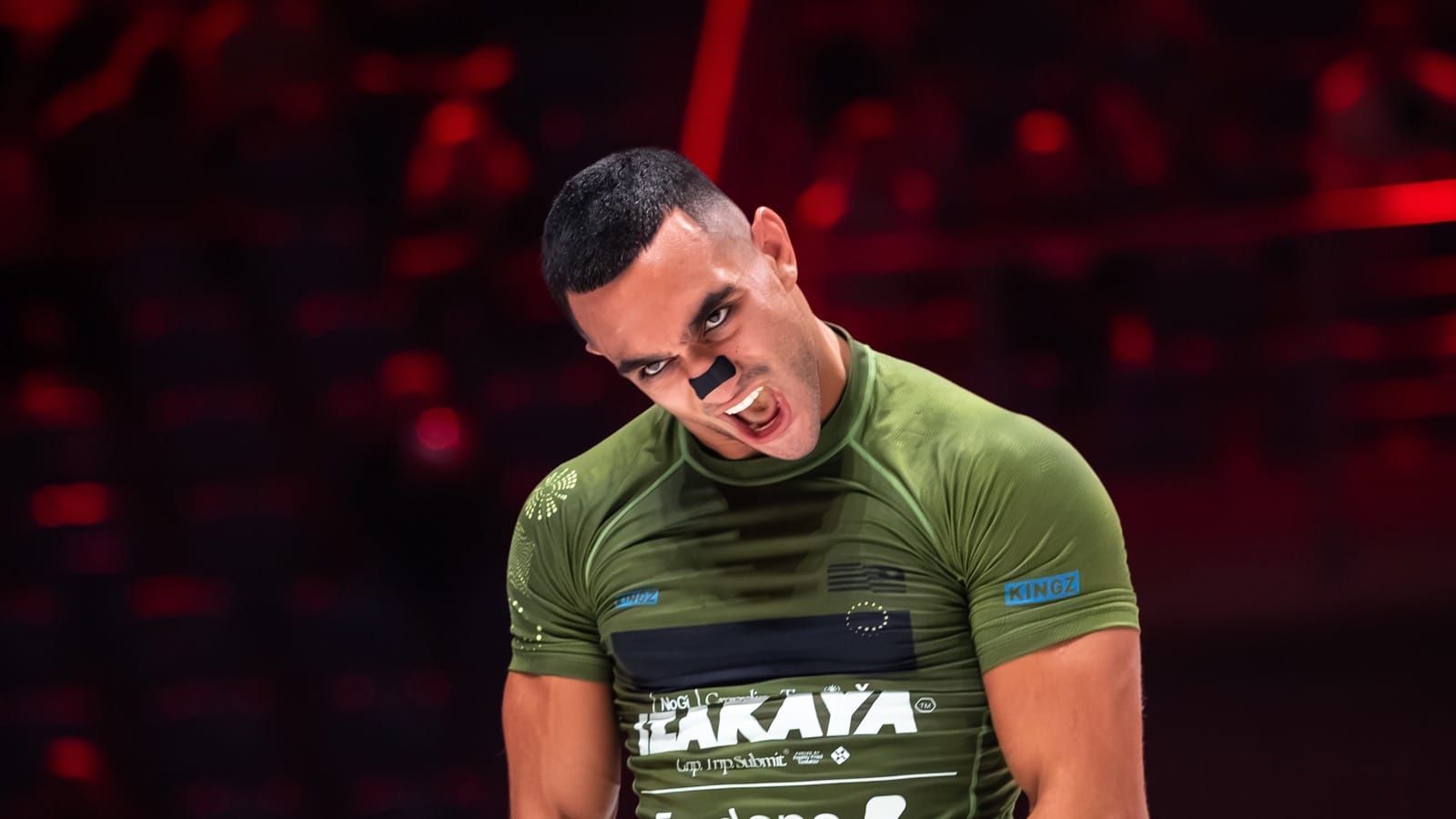 ADCC 2026 competitor celebrates under red arena lights after advancing on day one in Krakow.