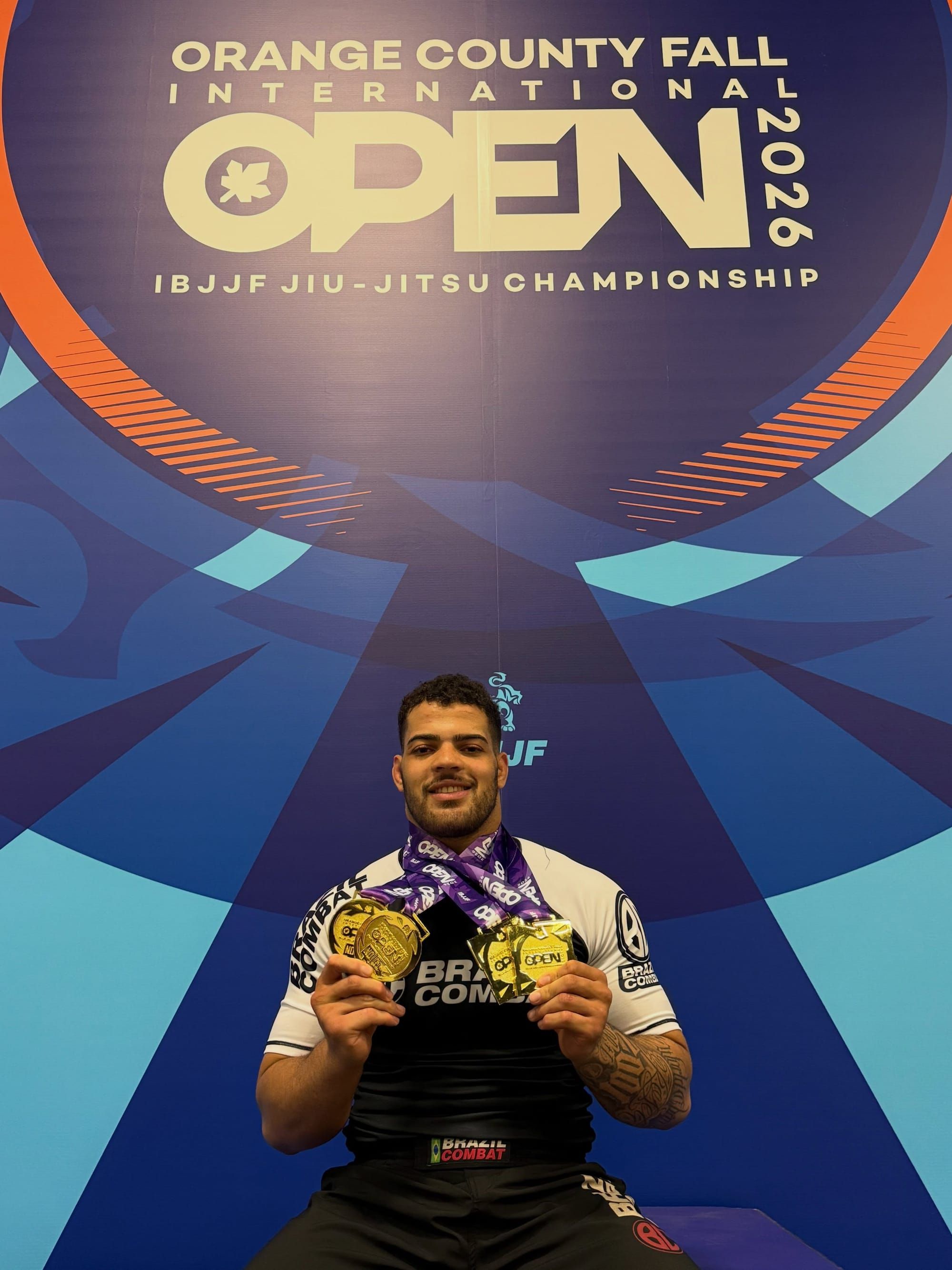 Adrian Roberto holding gold medals in front of the Orange County Fall Open 2026 backdrop.