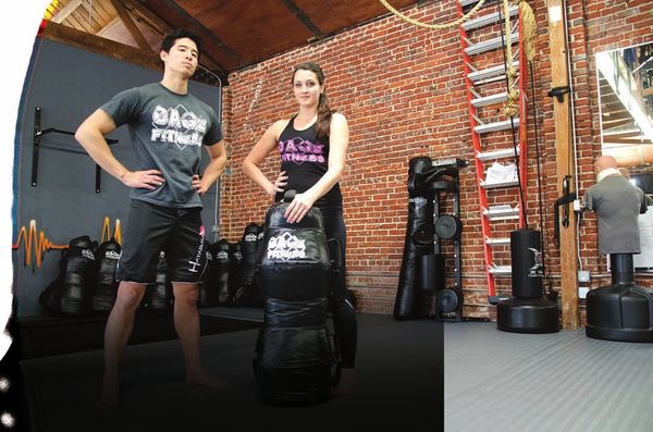 Jon Lee Brody and Kelly Babb standing with Cage Fitness training dummies at XMA World Headquarters.