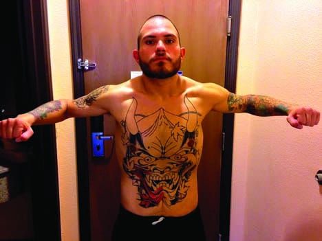 Ozzy Rivera stands shirtless with his arms extended after his weight-loss transformation.