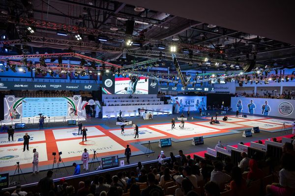 Multiple jiu-jitsu matches taking place on red-and-white mats inside Mubadala Arena during the Abu Dhabi World Professional Jiu-Jitsu Championship.