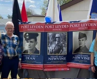  My dad Ed Newvine stands next to military banners honoring family members who served in the military.  Chester T. Dean is memorialized with a banner honoring his service in World War II .   