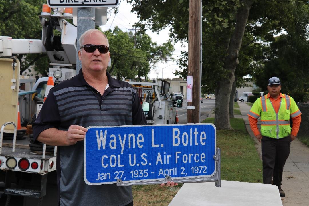  Mark Bolte, the son of Air Force Colonel Wayne Bolte holds the sign that honors his dad along M Street (Veterans Boulevard) in Merced. Photo: City of Merced 