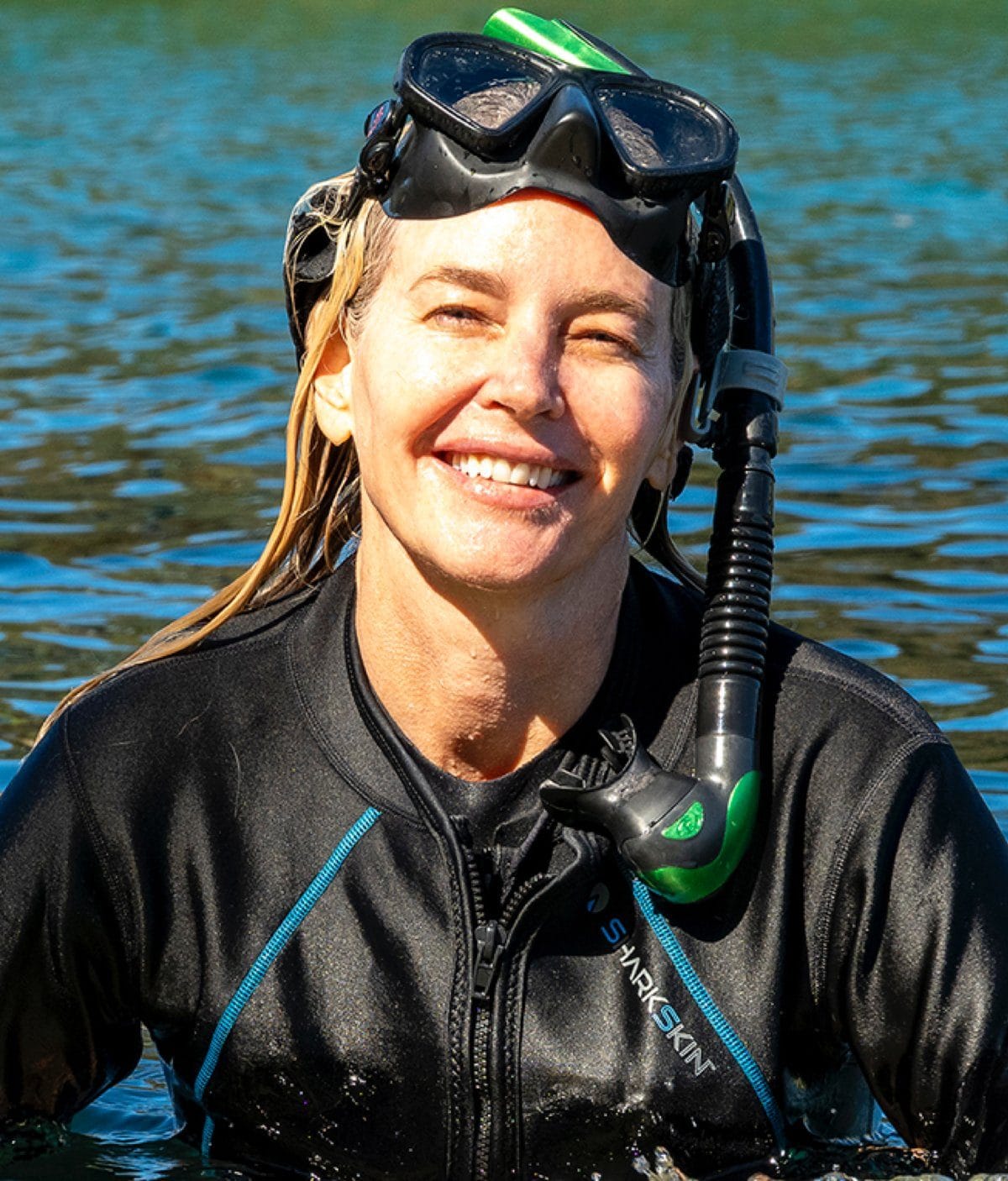 Nicole smiling in the water in a wetsuit, with a snorkel and mask pushed up on her head