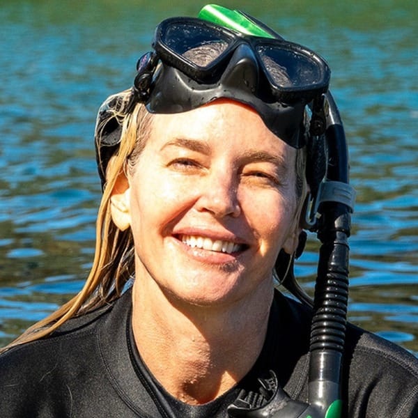 Nicole smiling in the water in a wetsuit, with a snorkel and mask pushed up on her head