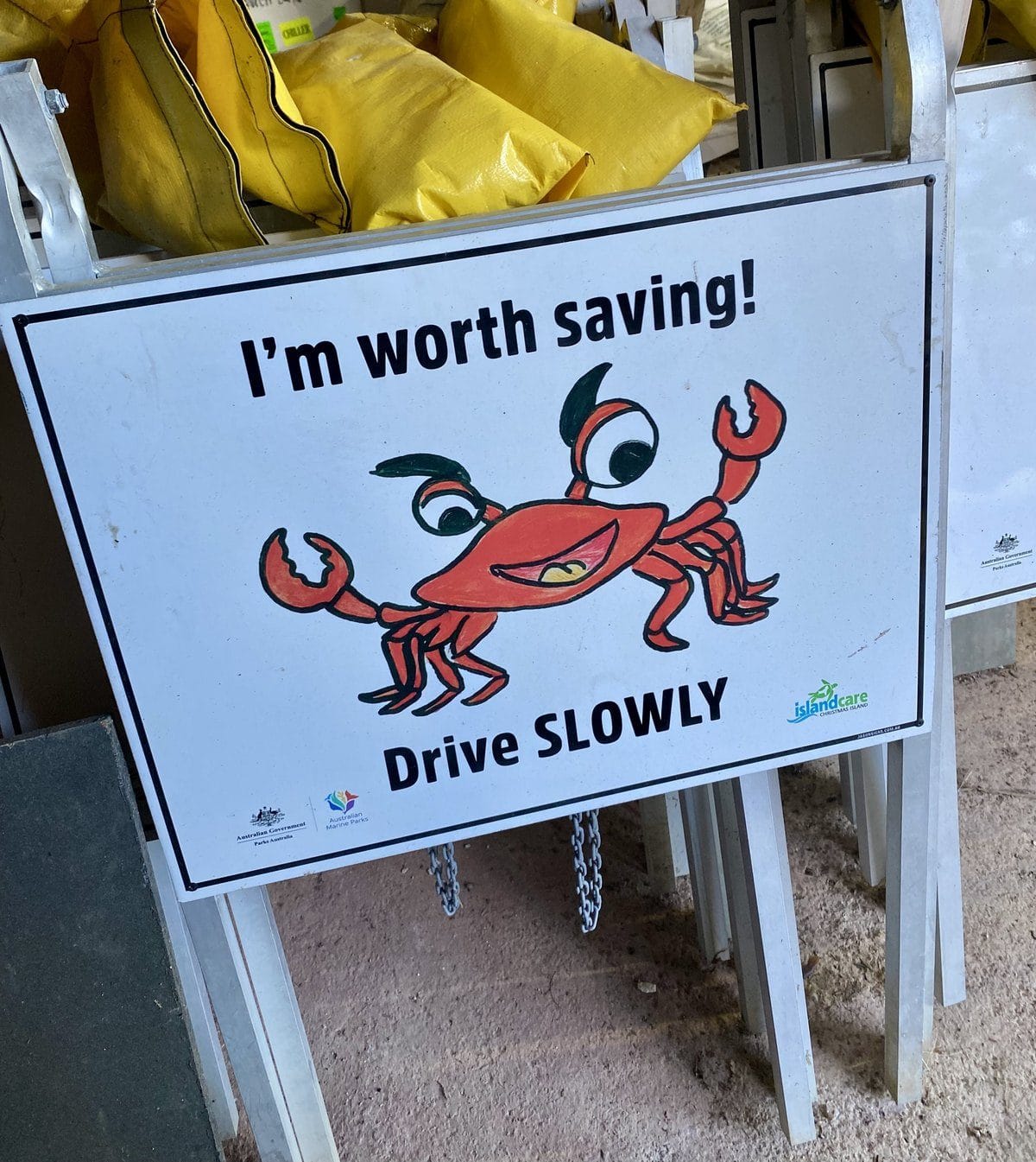 A hand painted road sign of a smiling red crab reading I'm worth saving, drive slowly, designed by Christmas Island school children
