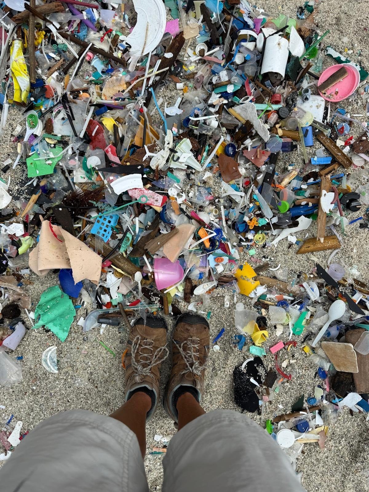 Nicole's shoes on the sand at Greta Beach, Christmas Island, surrounded by colourful marine debris washed in by the ocean