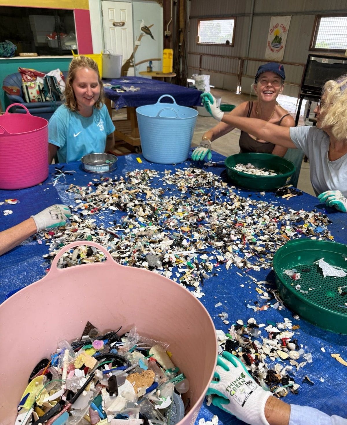 Volunteers smiling at the sorting table, counting and categorising colourful pieces of marine debris into tubs