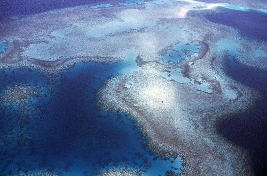 An aerial view of turquoise reef patterns in deep blue sea, Torres Strait