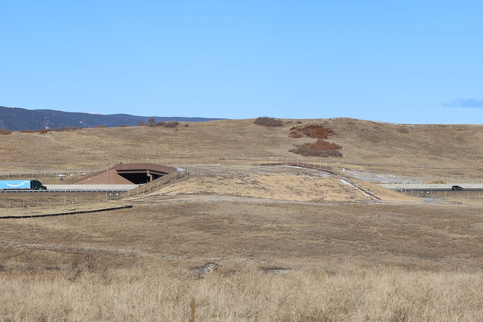 A wide earth covered bridge crossing a six lane highway