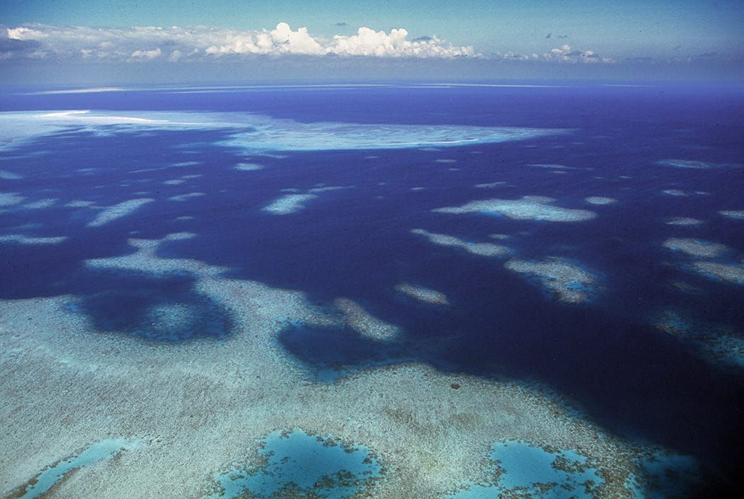 Aerial view of pale coral shallows meeting deep blue water in the Torres Strait, photographed by Oliver Strewe