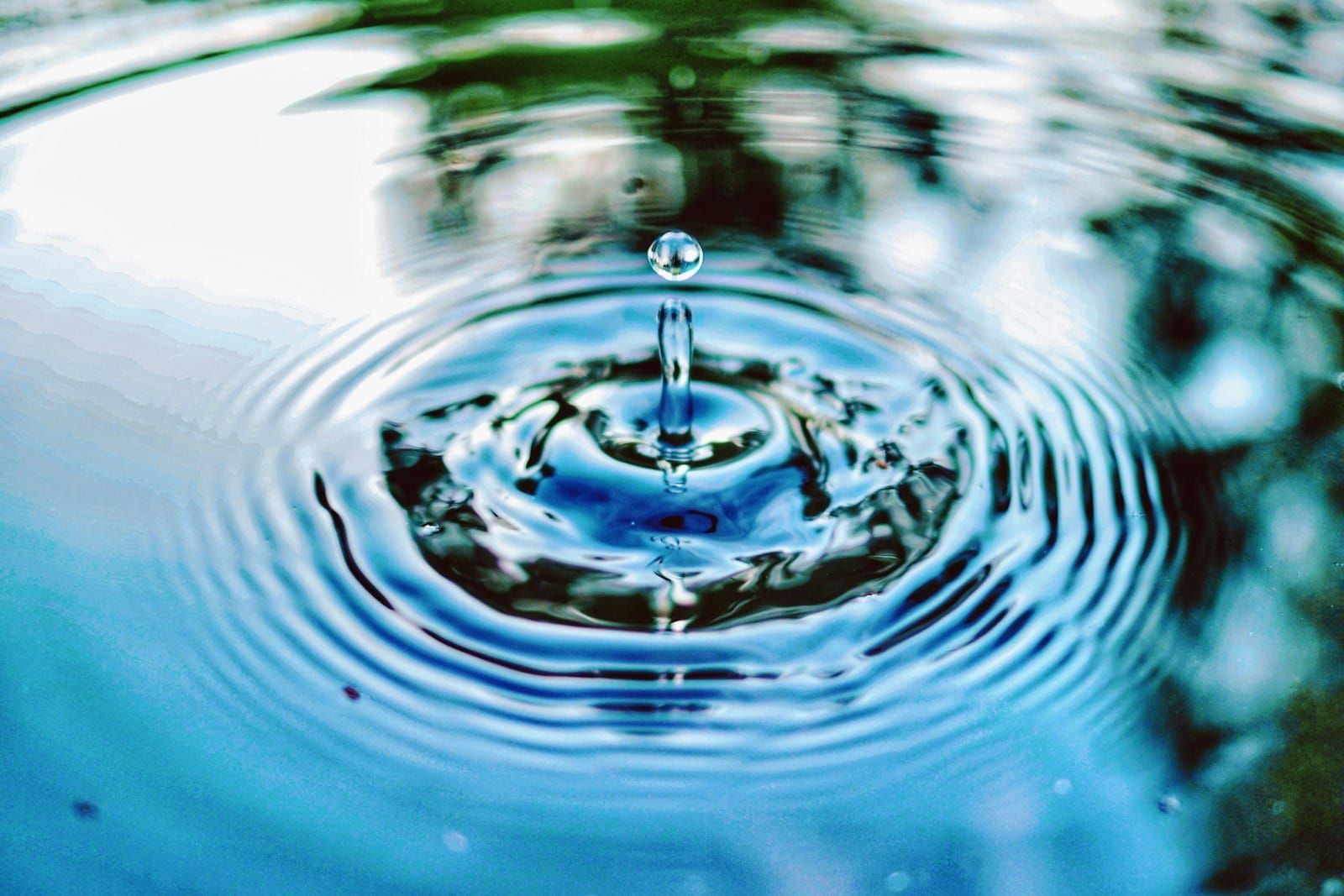 A single drop of water falling into still water, sending out rings