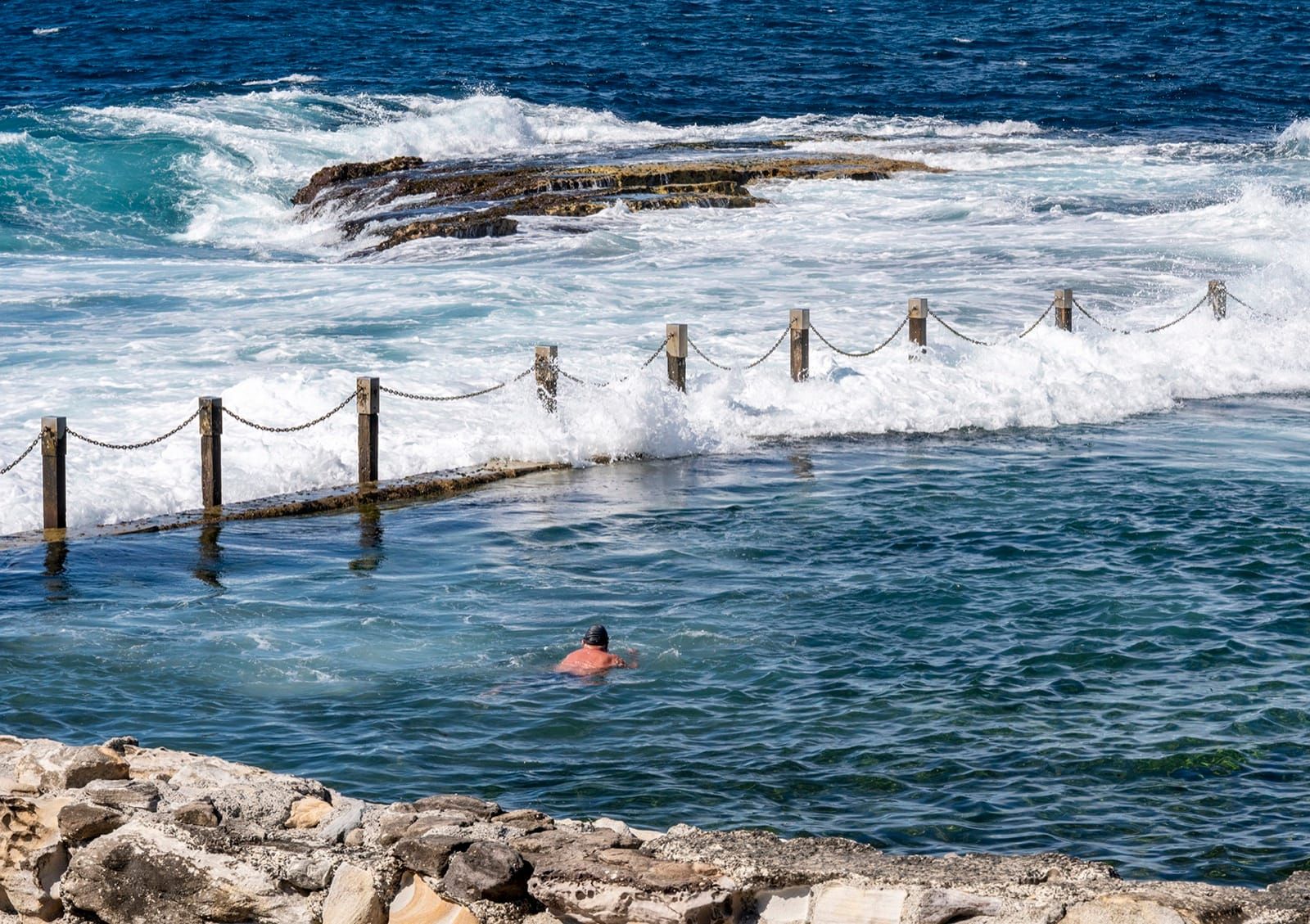 Surf breaks over the chain wall at Mahon Pool, Maroubra