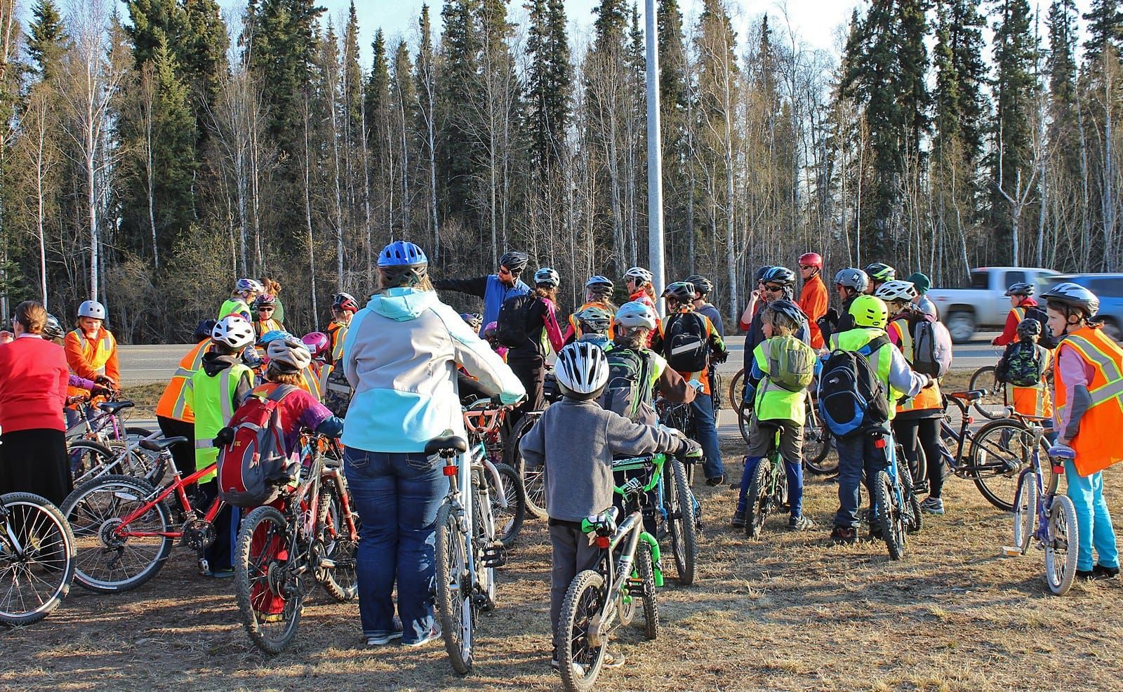 A group of children in helmets and high visibility vests gathered on their bikes before riding to school