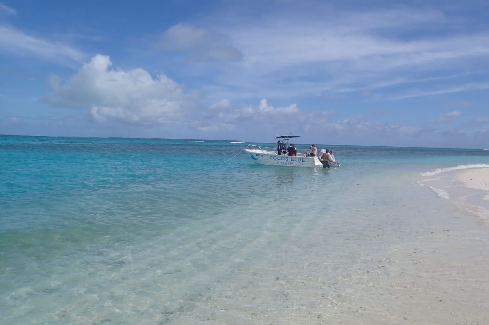 A small charter boat at the sand spit of Horsburgh Island, Cocos (Keeling) Islands, clear turquoise water and white sand