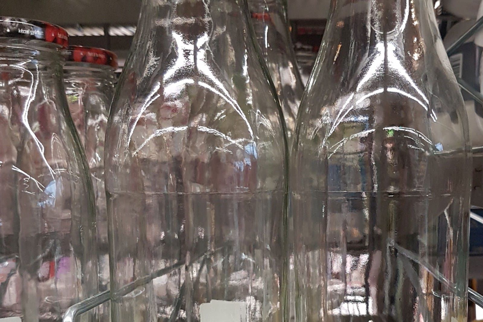 Rows of empty clear glass milk bottles standing in a crate