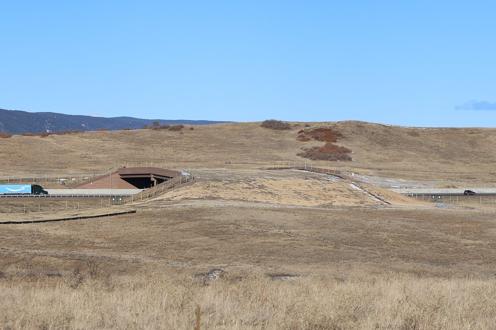 A wide earth covered bridge crossing a six lane highway