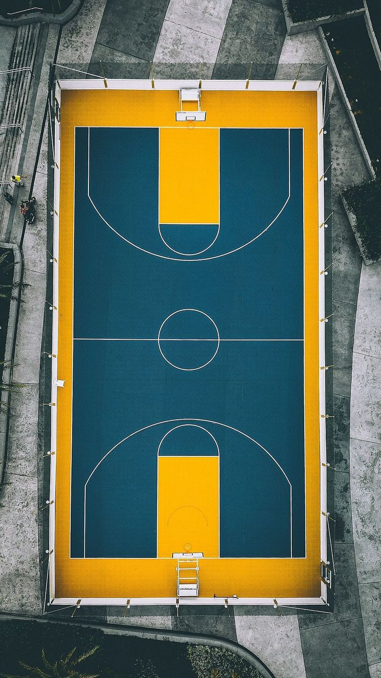 A basketball court painted teal on a golden yellow surround, seen from directly above, a stand in for the South Jamaica water squares