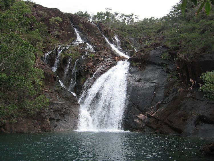 Zoe Falls tumbling down dark rock into a deep green pool on Hinchinbrook Island