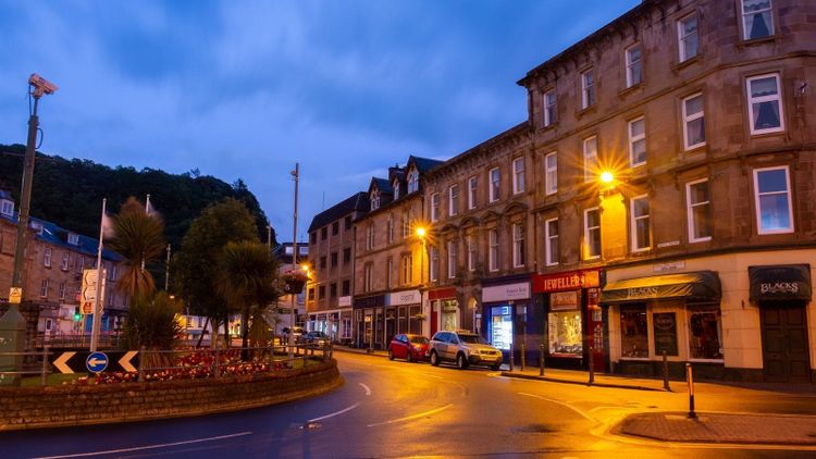A warmly lit town street on a soft blue evening