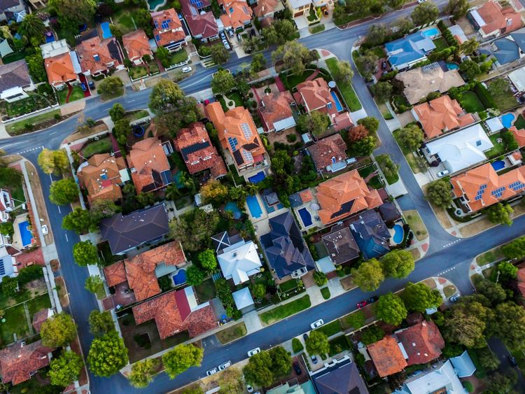 An Australian suburb from above, rooftops, pools and solar panels in the sun