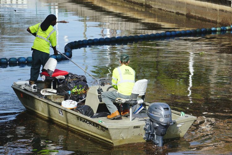 Workers collecting floating rubbish from a river