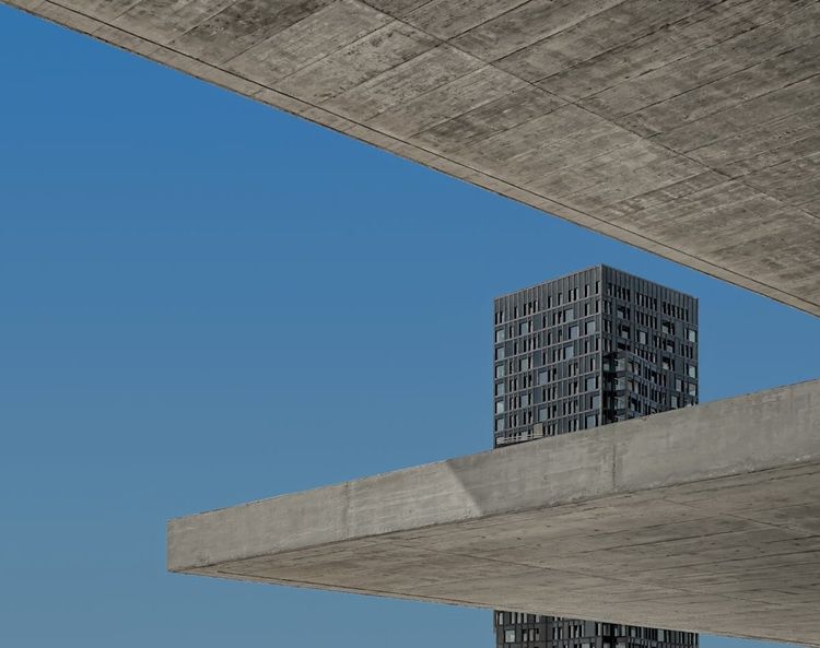 Two concrete slabs framing a blue sky with an apartment tower between them
